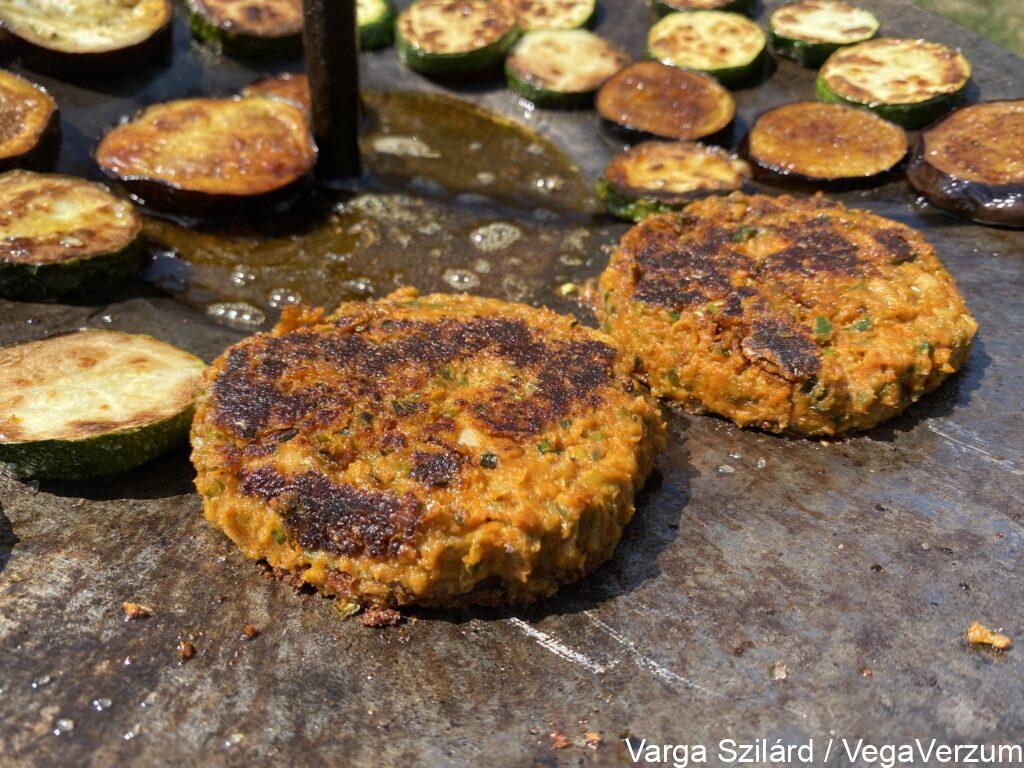Fehérbabos hamburger pogácsa átfordítás után sütés közben cukkinival és padlizsánnal szabadtéren parázs felett tárcsalapon sütve