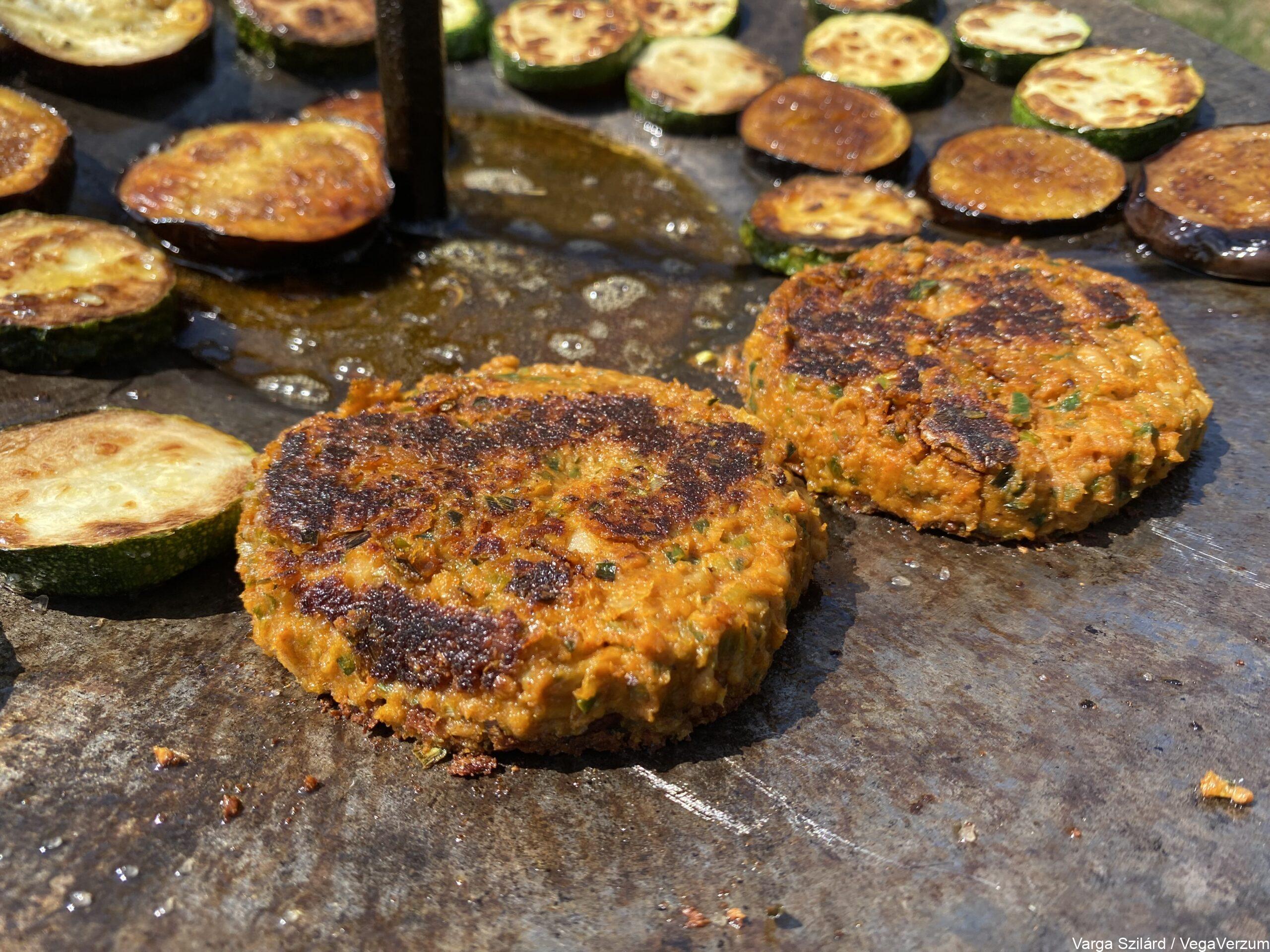 Fehérbabos hamburger pogácsa átfordítás után sütés közben cukkinival és padlizsánnal szabadtéren parázs felett tárcsalapon sütve